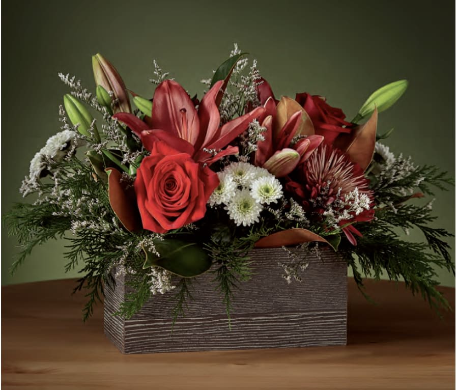 Red floral arrangement in a rectangular wooden box with lilies and roses