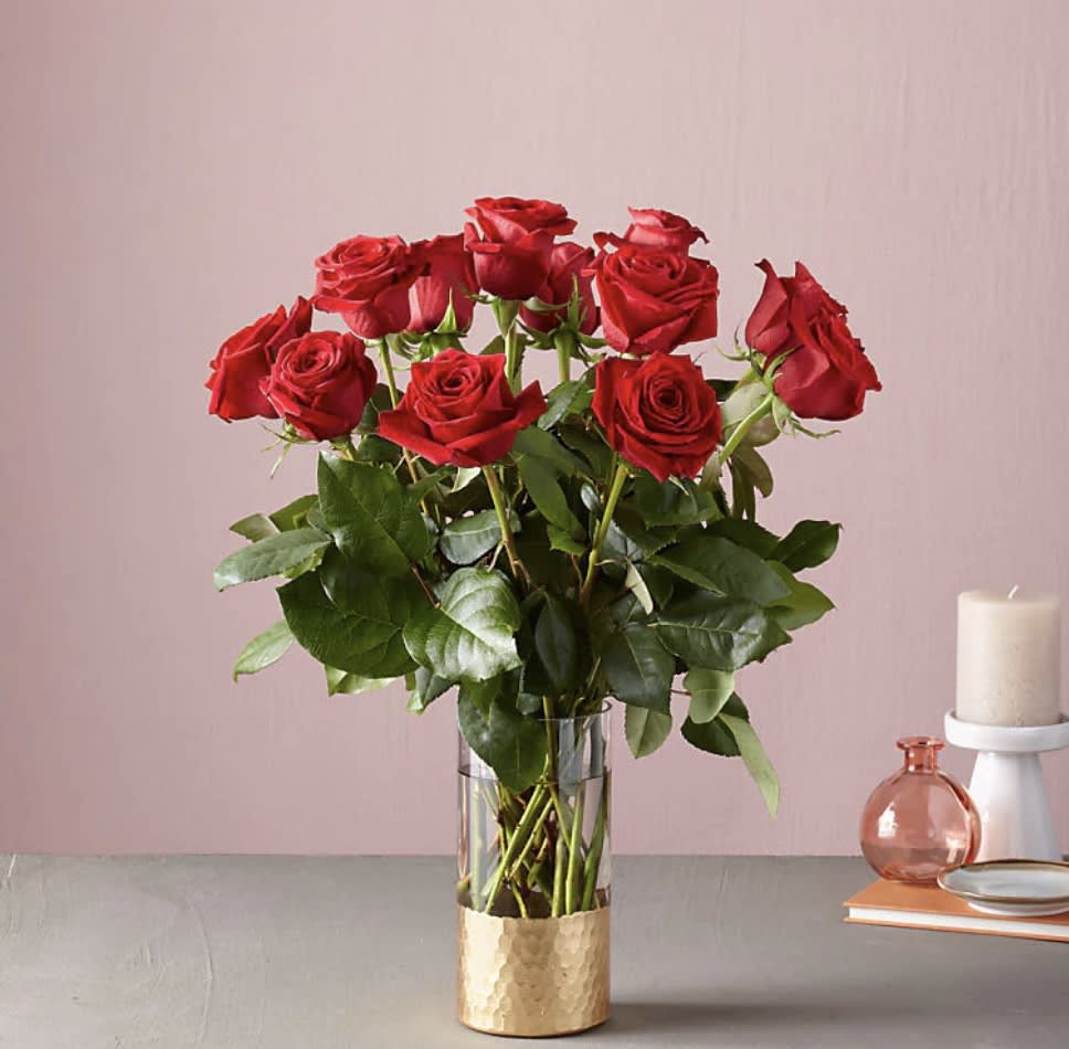 Red roses in a clear glass vase with a gold base
