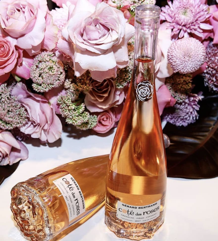 Pink roses with a rosé wine bottle and glass on a table
