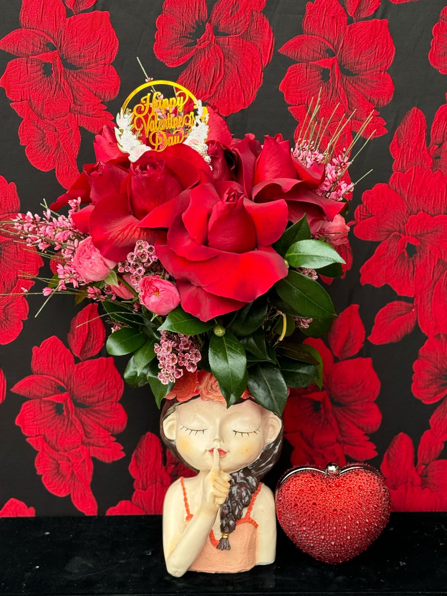 Girl in Love: with heart shaped clutch  - A stunning combination of passionate red roses arranged elegantly in a beautiful vase, perfectly paired with a chic red clutch that embodies both romance and sophistication. This set is designed for the girl in love, blending the timeless beauty of red roses—a symbol of deep affection—with the modern charm of the vibrant, eye-catching clutch. The roses express timeless love, while the clutch adds a touch of glamour, making it a perfect gift. Whether for a romantic date or a special celebration, the arrangement captures both elegance and heartfelt emotion, creating a memorable moment that will adorn any evening with grace.