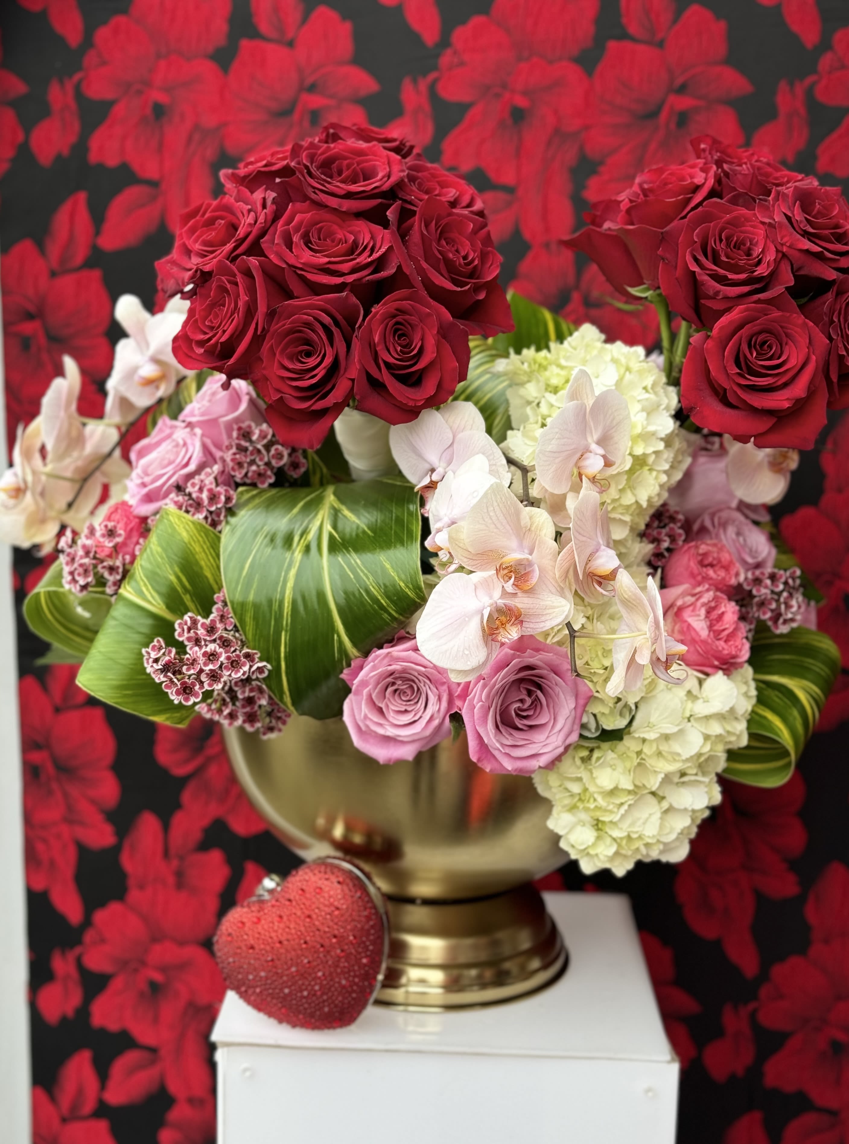 Abundant Love - A stunning statement piece featuring a large gold base, adorned with lush white hydrangeas, elegant orchids, and soft pink roses. This arrangement radiates love and sophistication, creating a striking display that captures the essence of luxury, elegance, love, and affection.