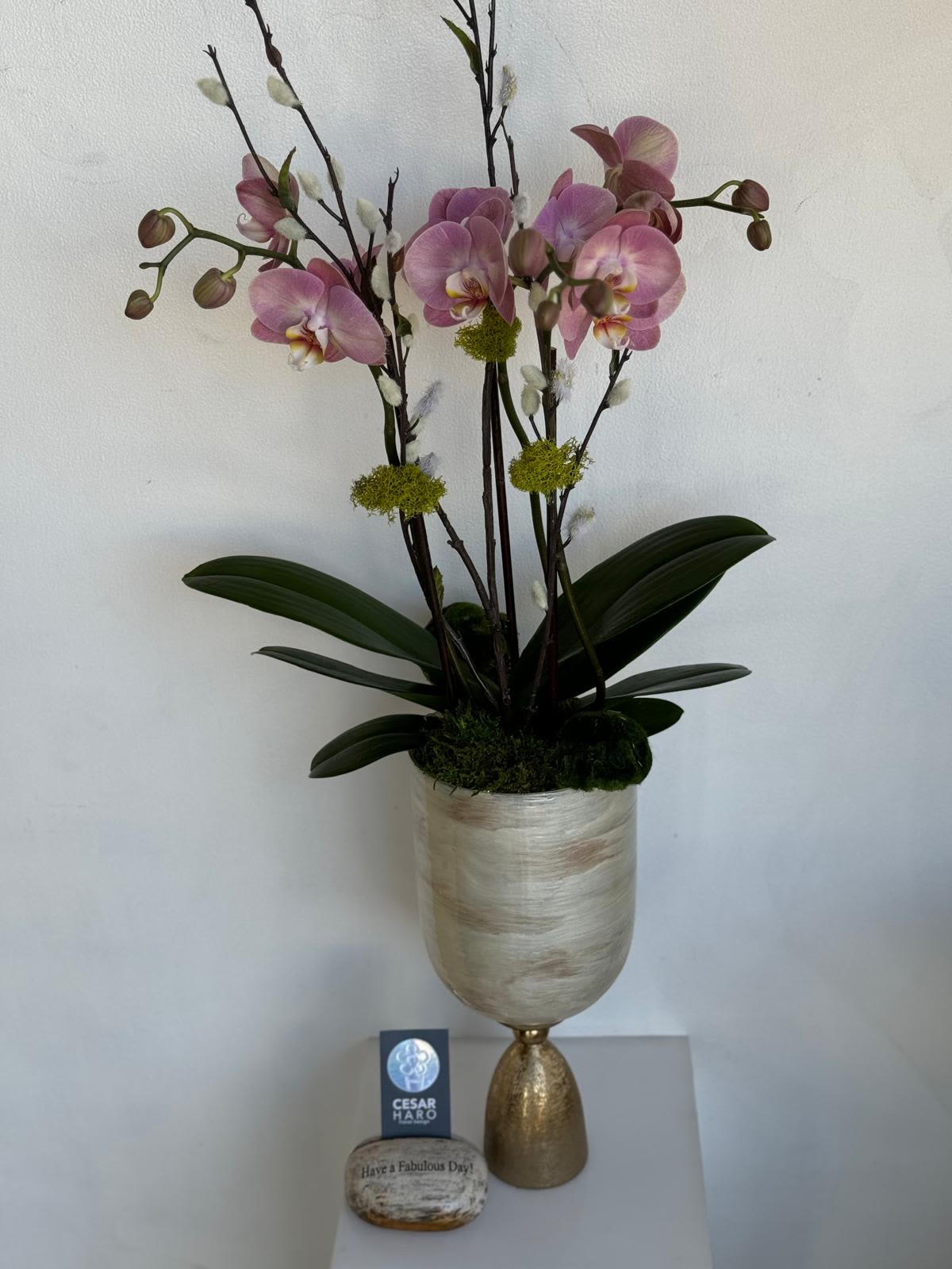 Opal Radiance - A luxurious arrangement showcasing pristine white orchids atop an opal-like pillar vase with elegant gold and pearly white accents. This refined and contemporary design radiates sophistication, making it an ideal gift that captures timeless beauty and grace.