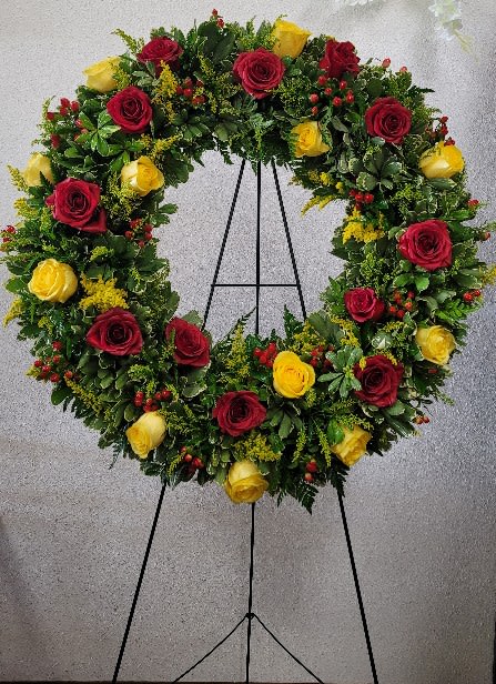 Heart-shaped wreath of red and yellow roses on an easel