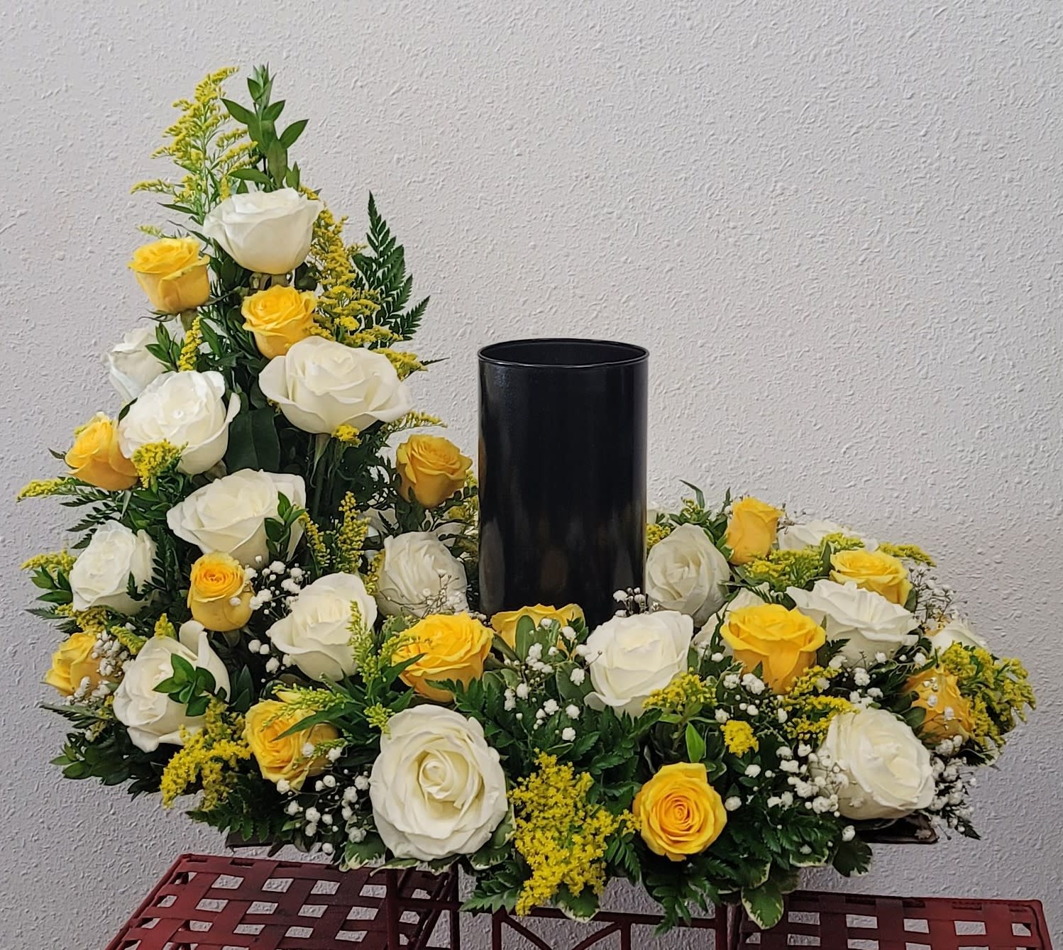 White and yellow roses arranged around a black vase