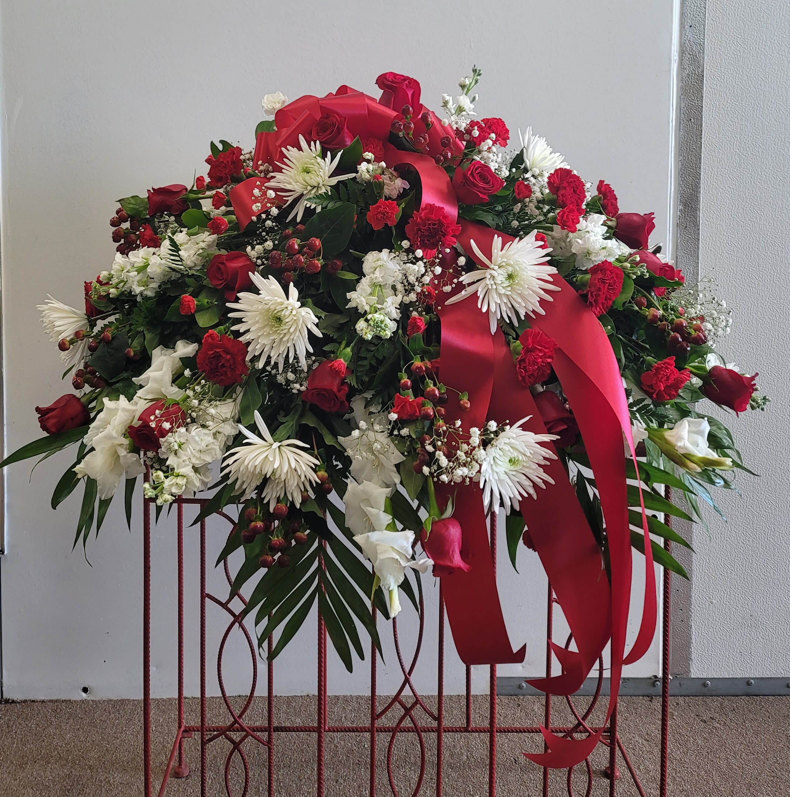 Large red and white floral spray with ribbon on a stand