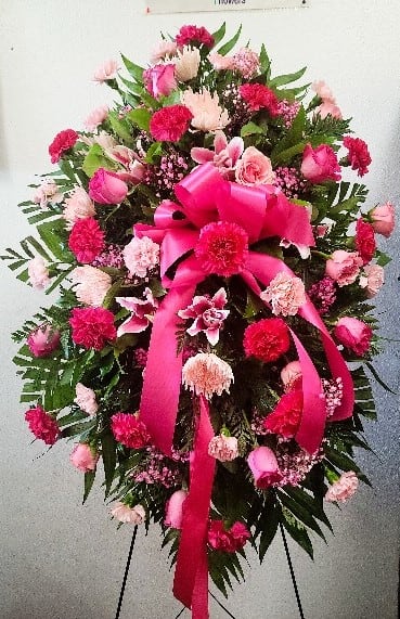 Pink and red funeral spray with ribbon on a standing easel