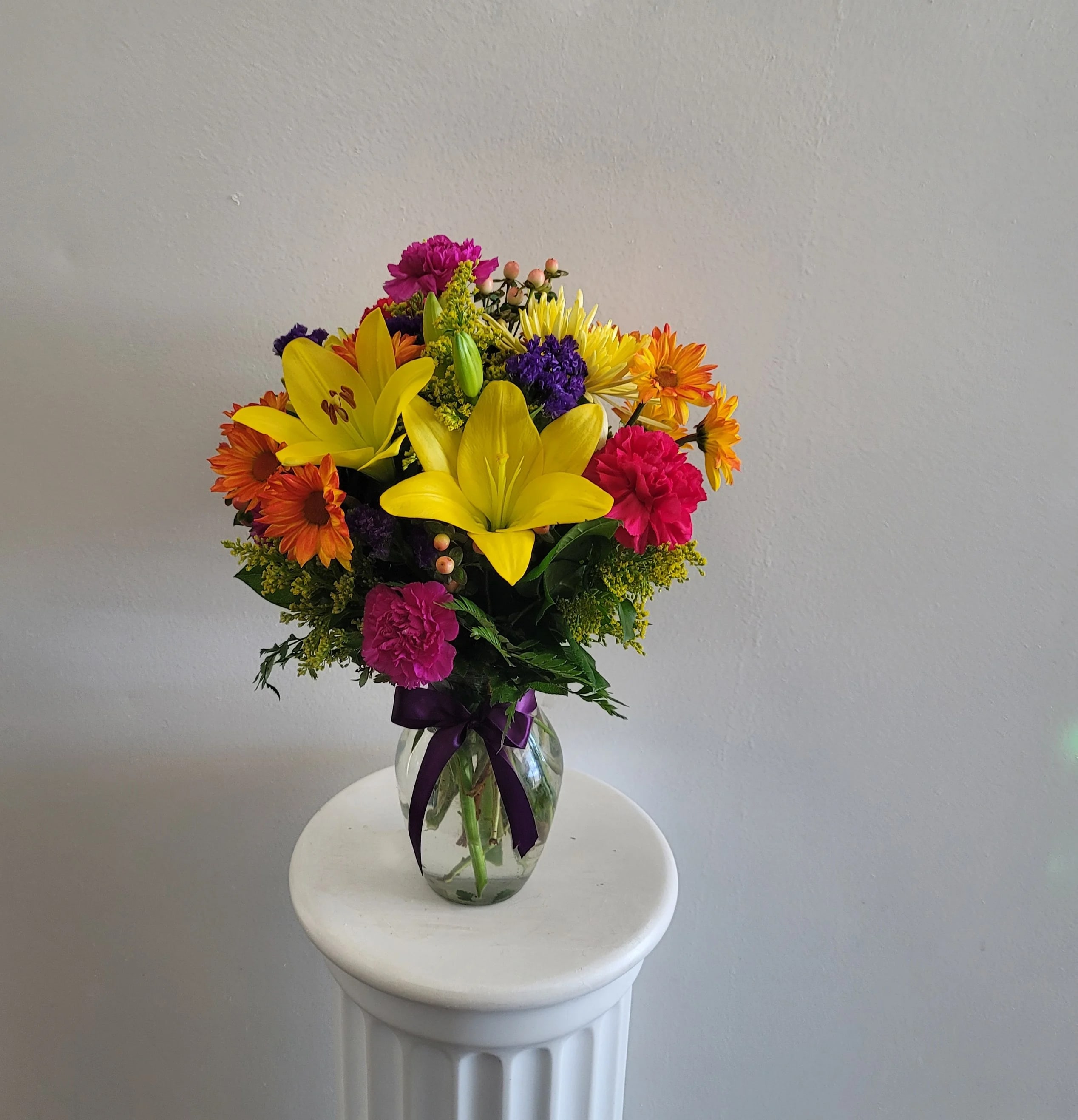 Colorful bouquet of lilies, daisies, and carnations in a glass vase