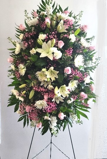 Tall standing floral spray with pink and white flowers on a black easel