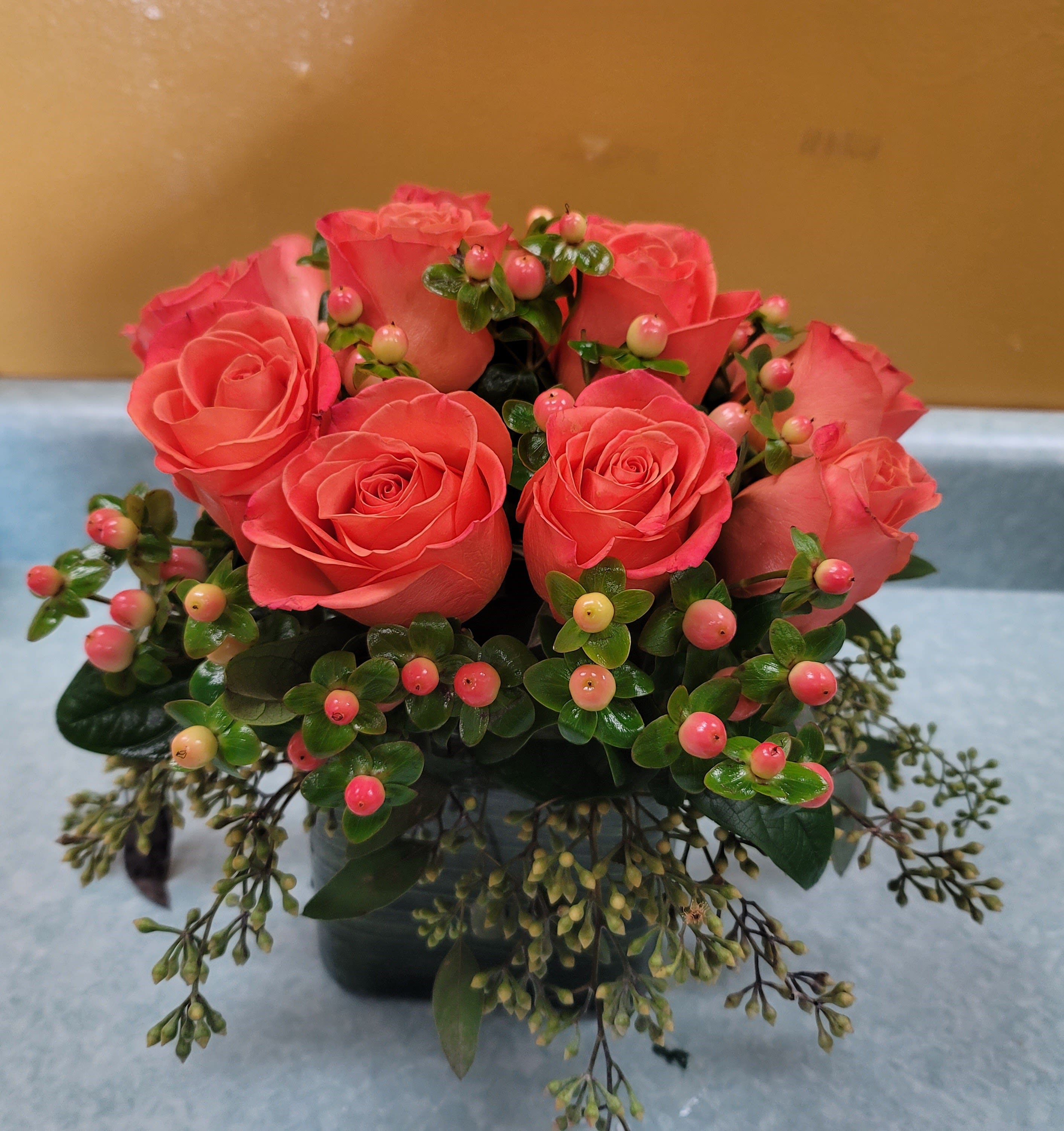 Pink roses arranged in a low vase with berry-like accents