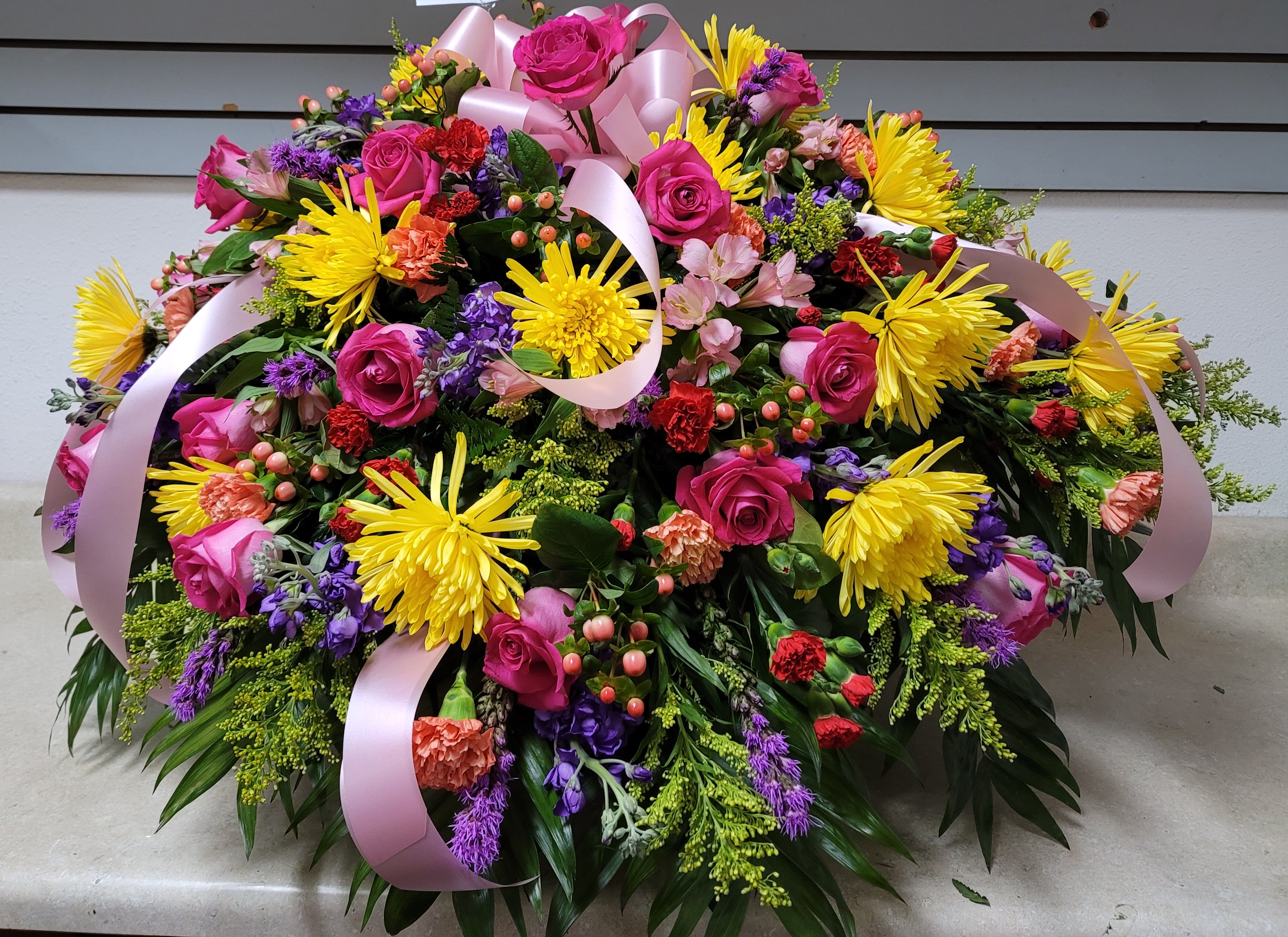 Large mixed bouquet of pink roses, yellow mums, and purple flowers with pink ribbon