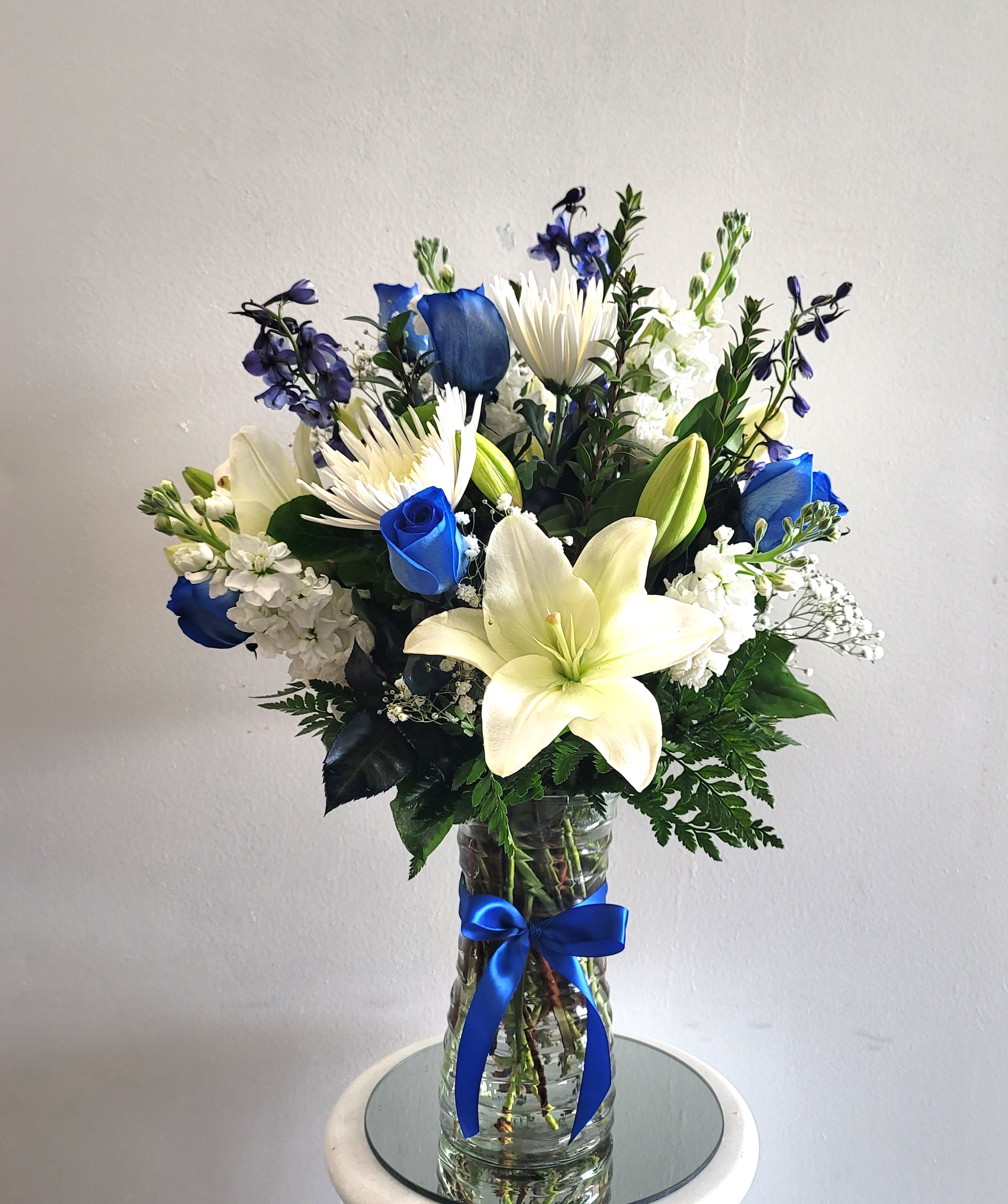 Blue and white bouquet with lilies and roses in a glass vase