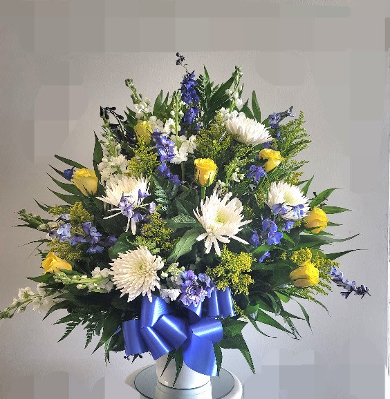 Large bouquet of white and yellow flowers with a blue ribbon in a white vase