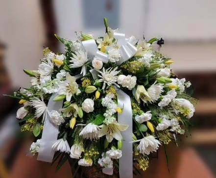 White floral spray with lilies and daisies tied with white ribbon