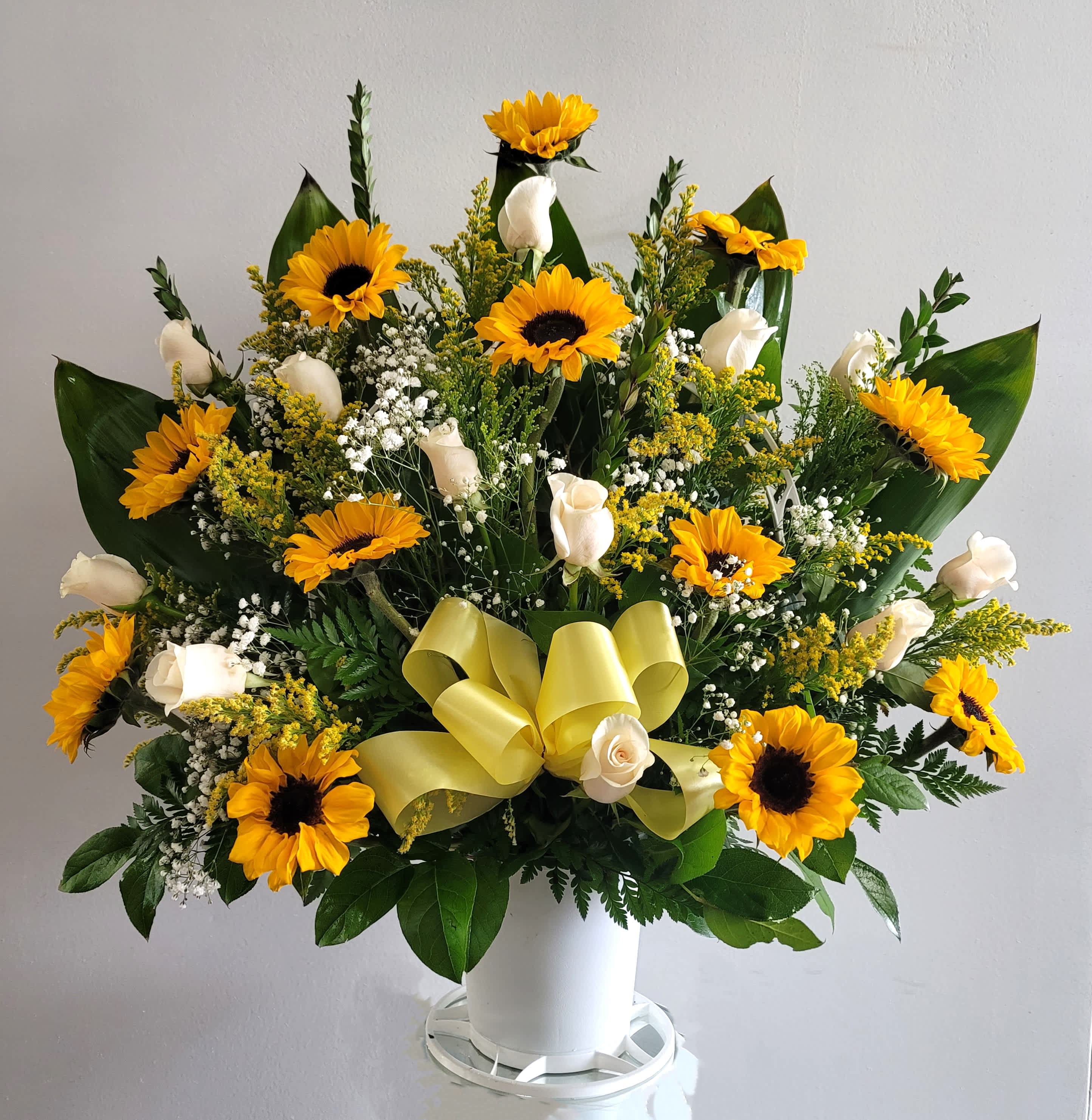 Large bouquet of yellow sunflowers and white roses in a white container