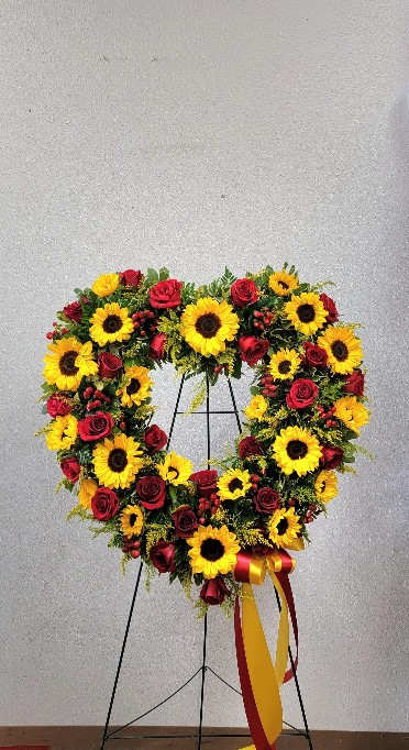 Heart-shaped wreath of sunflowers and red roses on a stand