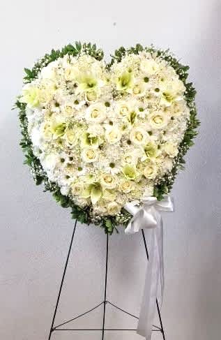 Heart-shaped white floral standing spray with a white ribbon