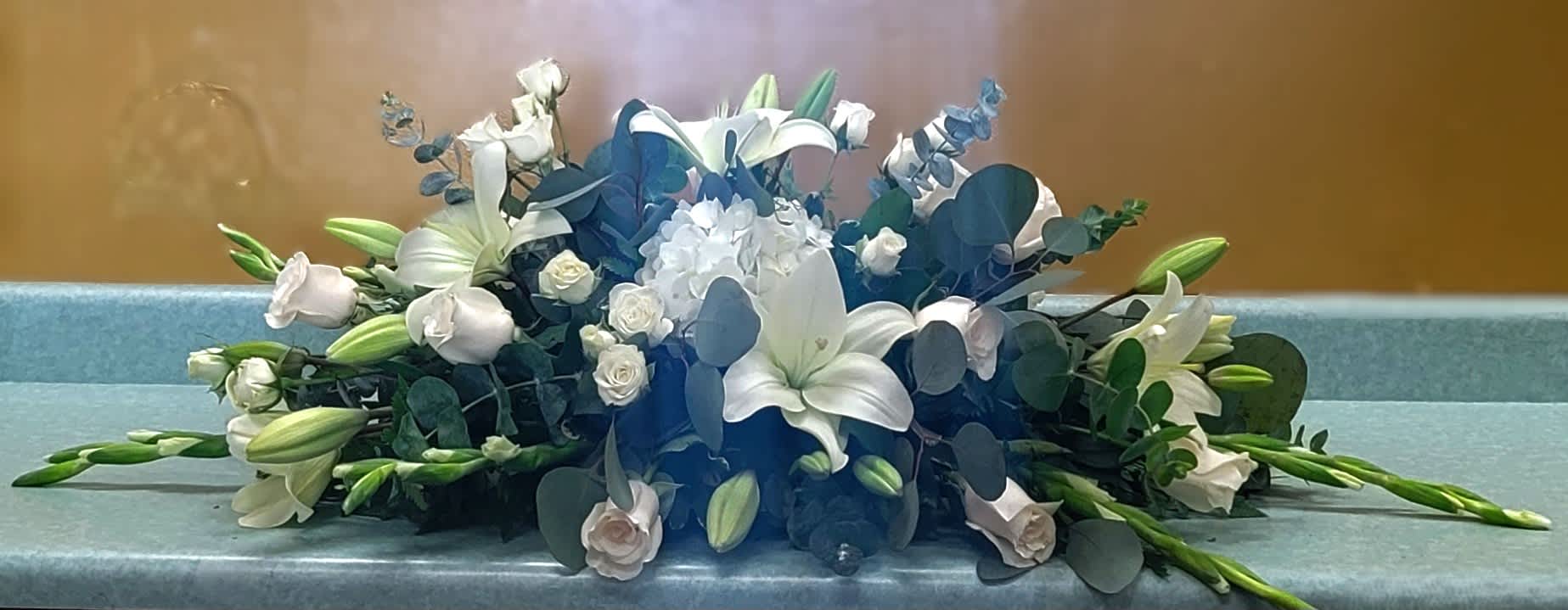 White lilies and roses arranged low with blue accents on a table