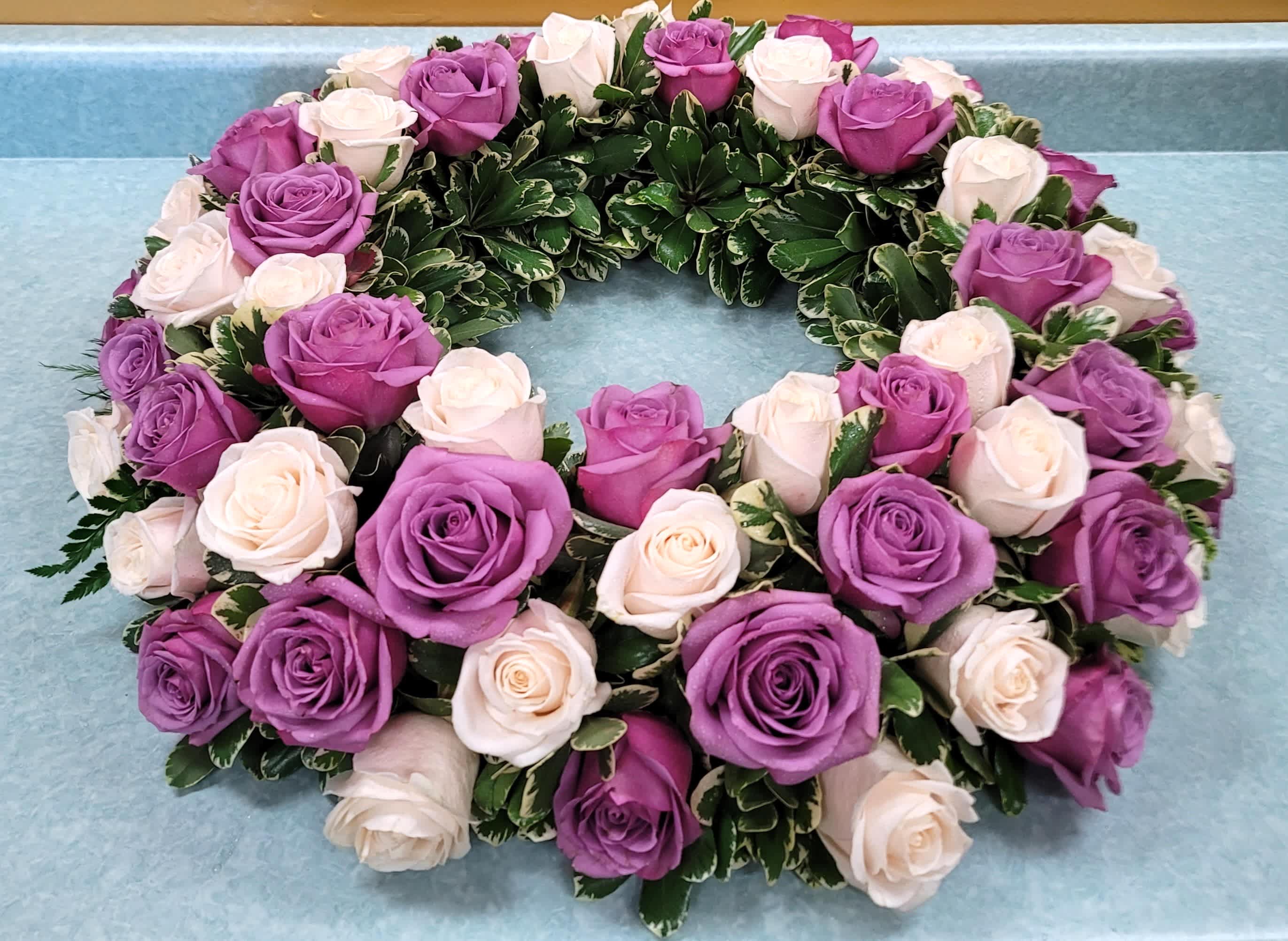 Circular wreath of purple and white roses on a blue surface