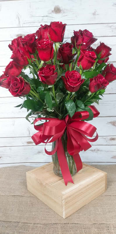 Bouquet of red roses in a glass vase with a red ribbon