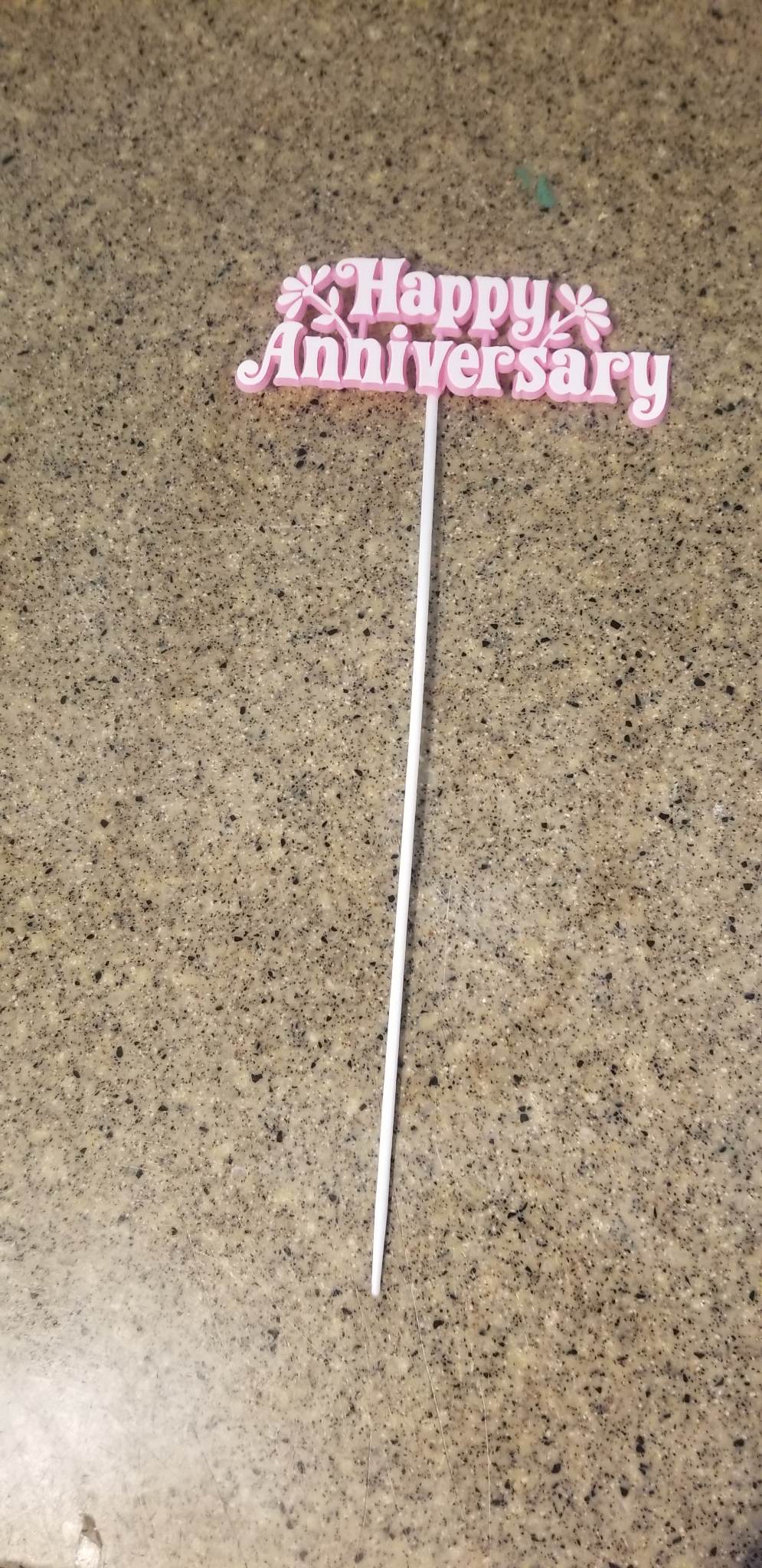 Pink "Happy Anniversary" cake topper on a white stick