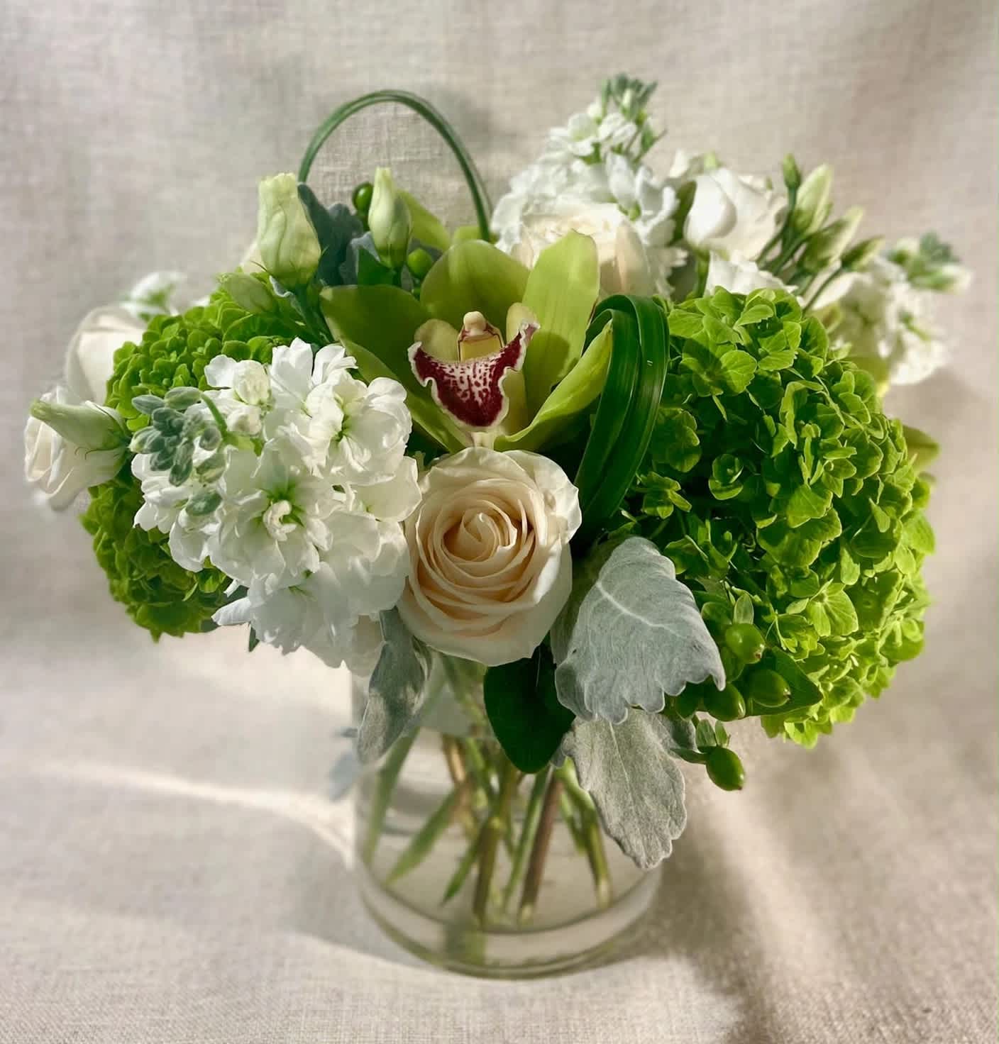 Green and white floral arrangement in a clear glass vase