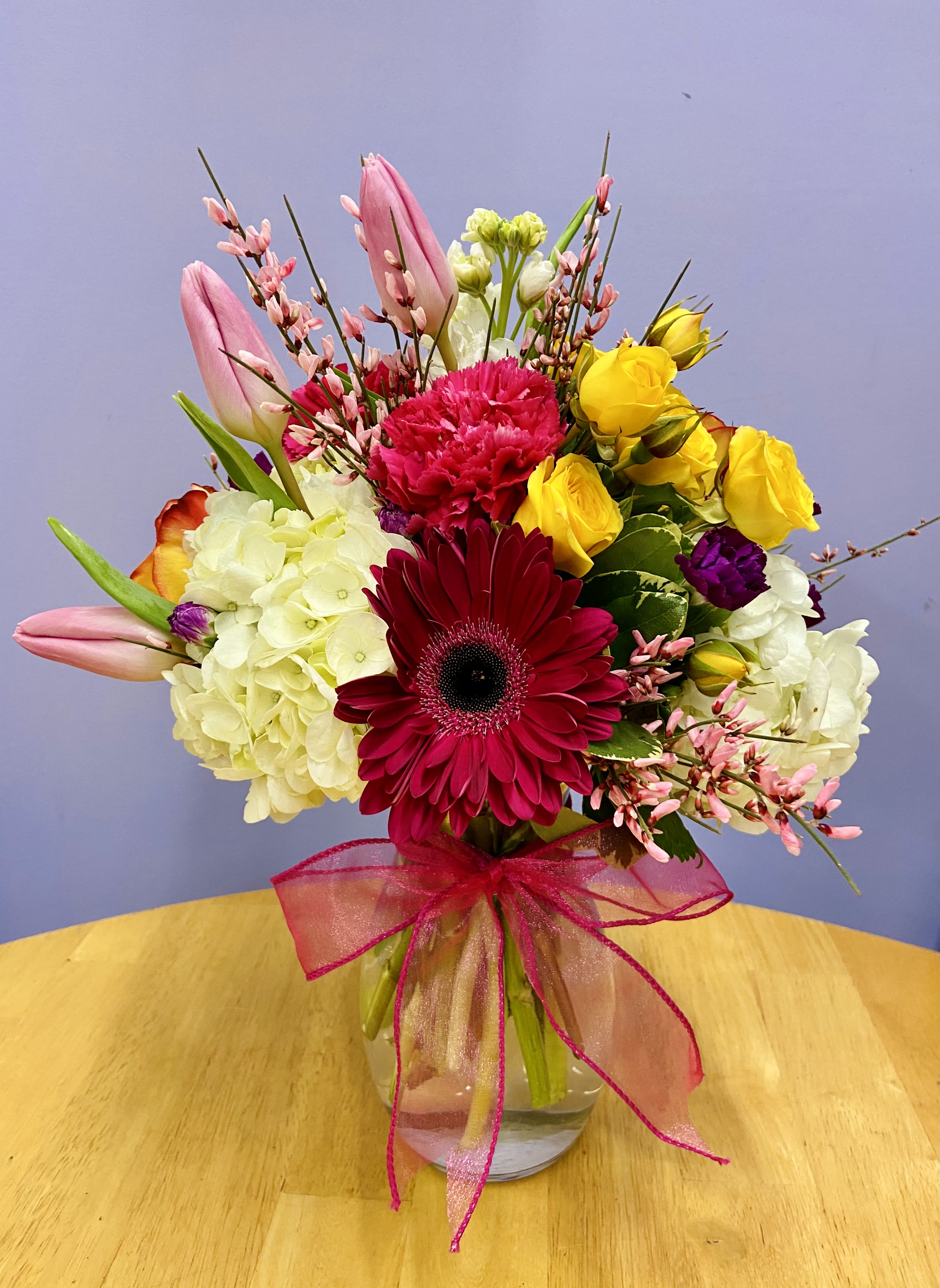 Mixed bouquet in a glass vase with pink, yellow, white, and red flowers