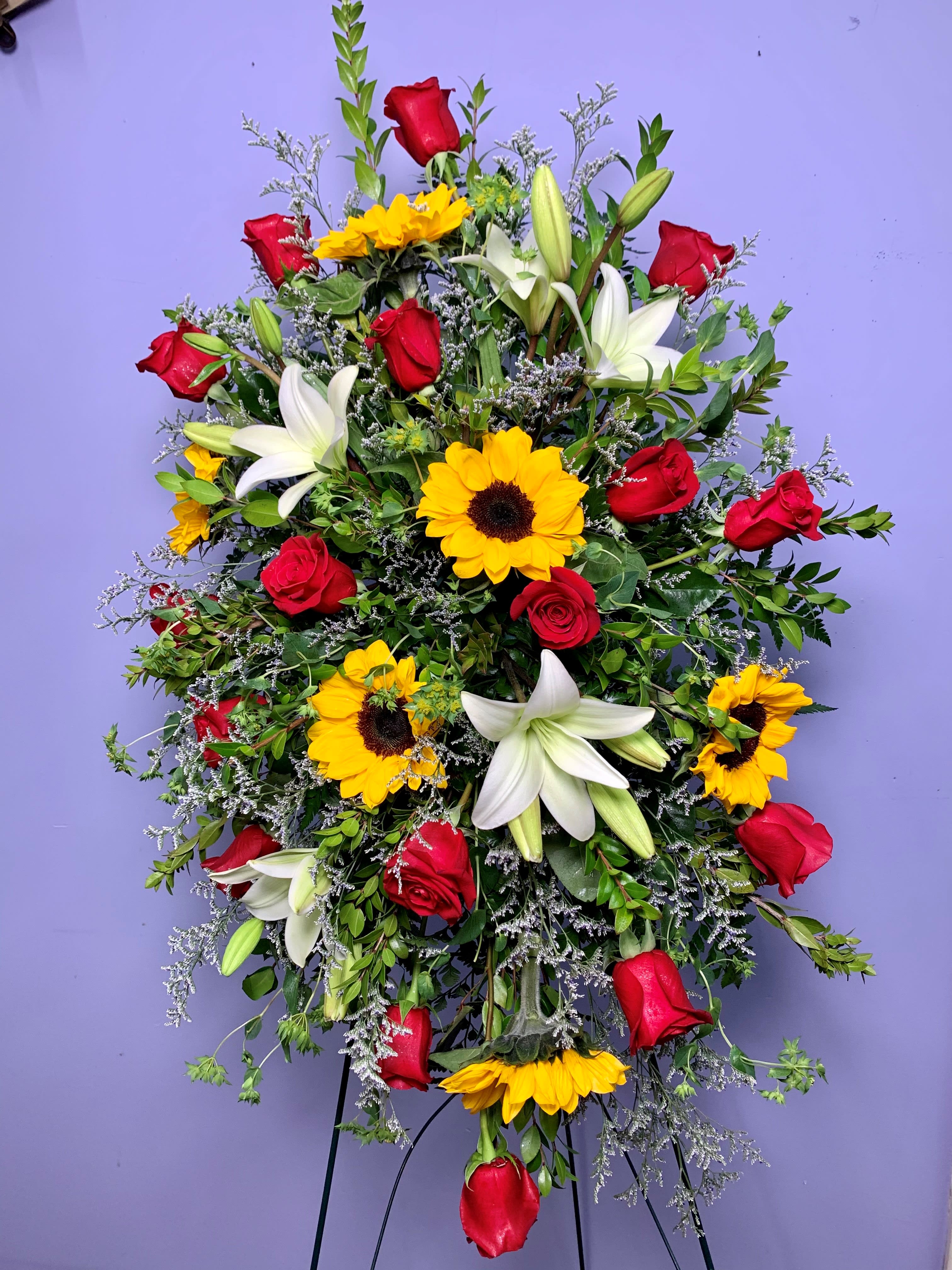 Standing spray with red roses, white lilies, and yellow sunflowers