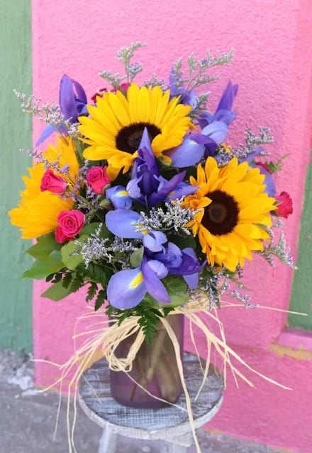 Bouquet of sunflowers, purple irises, and pink roses in a vase