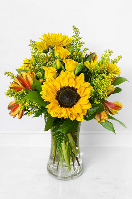 Yellow sunflower and rose bouquet in a clear glass vase