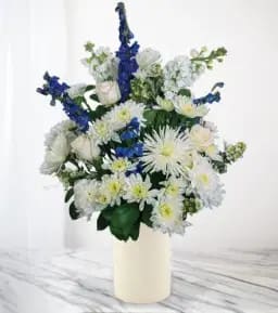White and blue flower arrangement in a cream vase