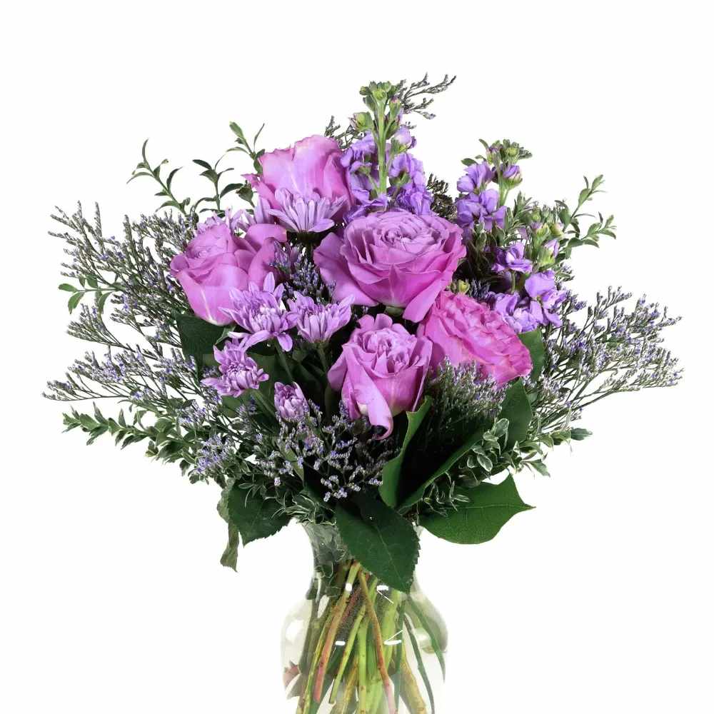 Purple roses and lavender flowers in a clear glass vase