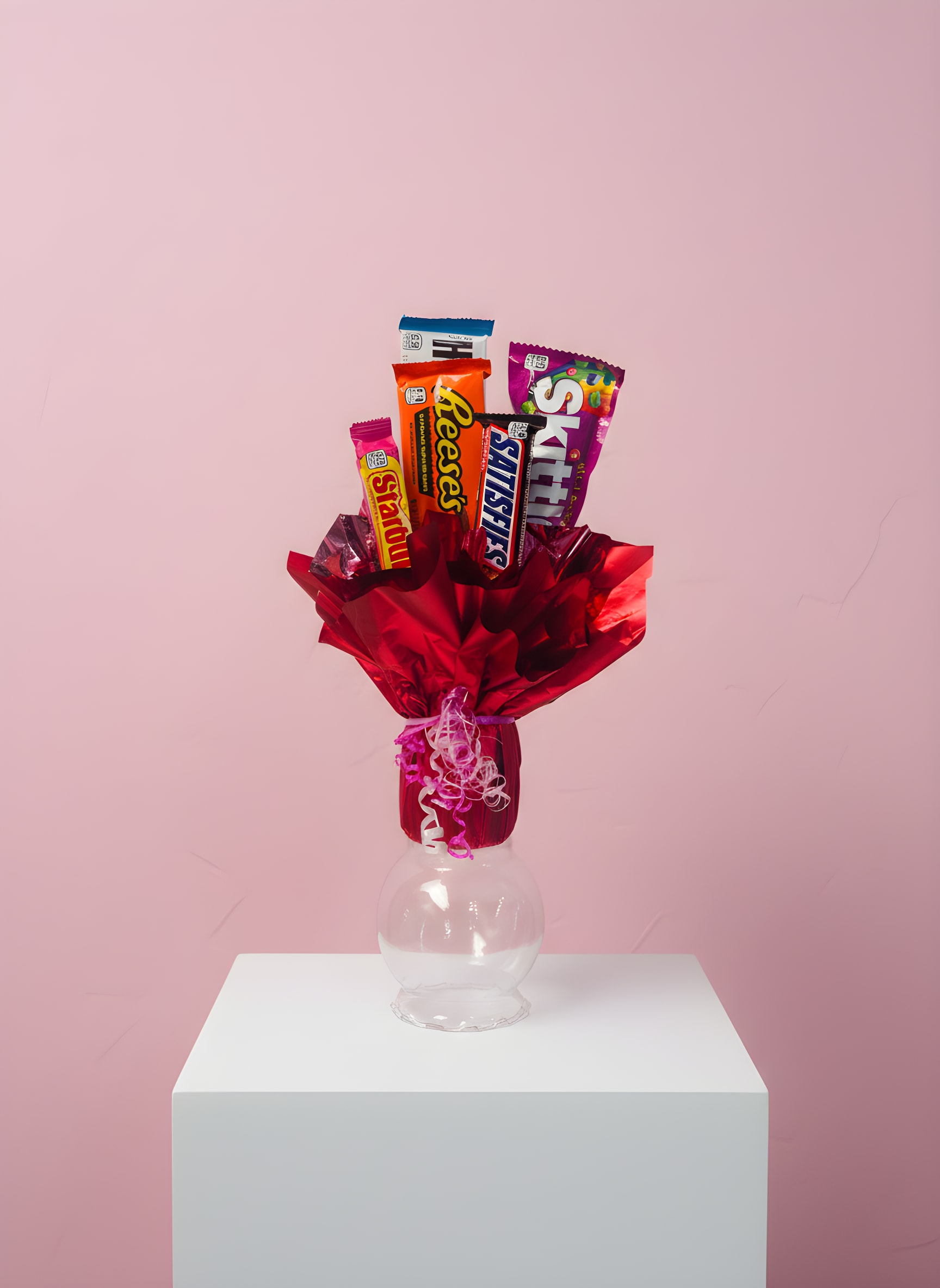 Candy bouquet in red wrapping with assorted chocolate bars in a clear vase