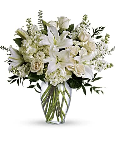 White lilies and roses arranged in a clear glass vase