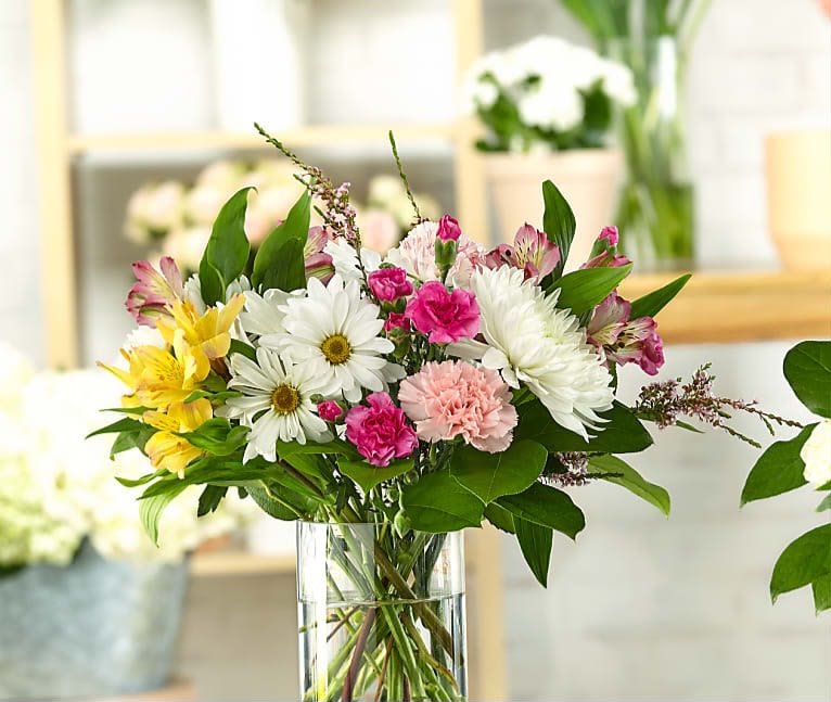 Mixed bouquet of daisies, carnations, and alstroemeria in a clear glass vase