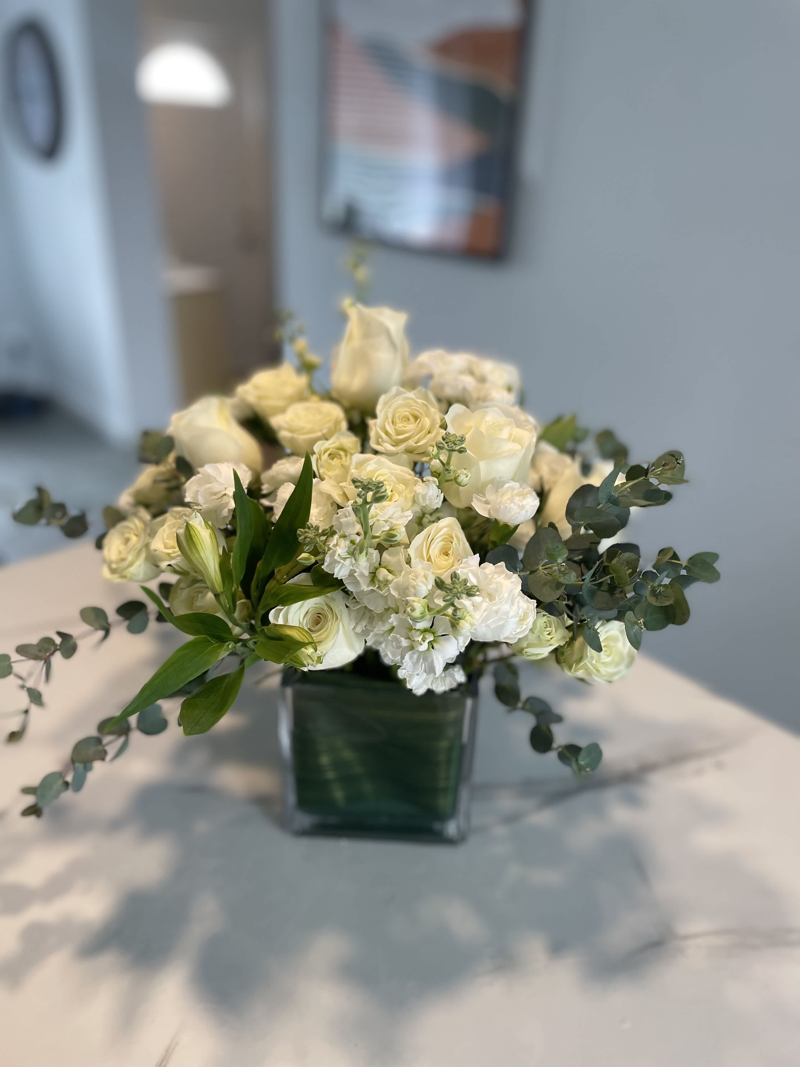 White Dream - White roses, white stock, assorted greens all in a medium green tai leaf vase