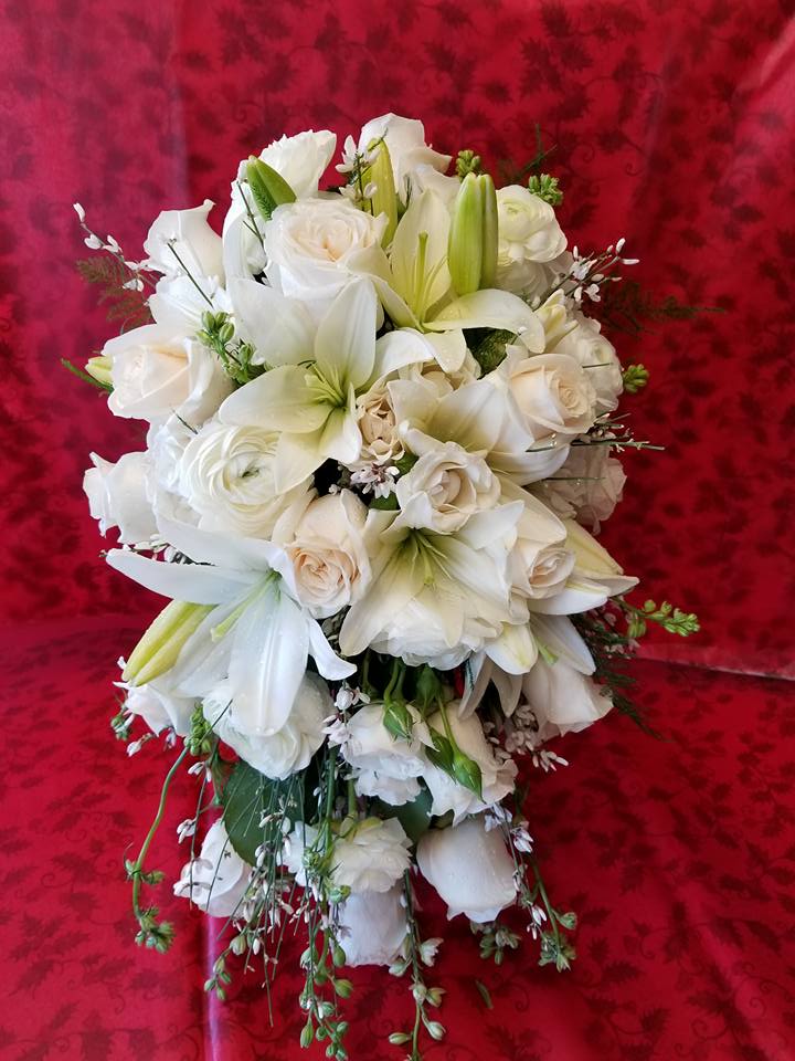 White bouquet of lilies and roses against a red background