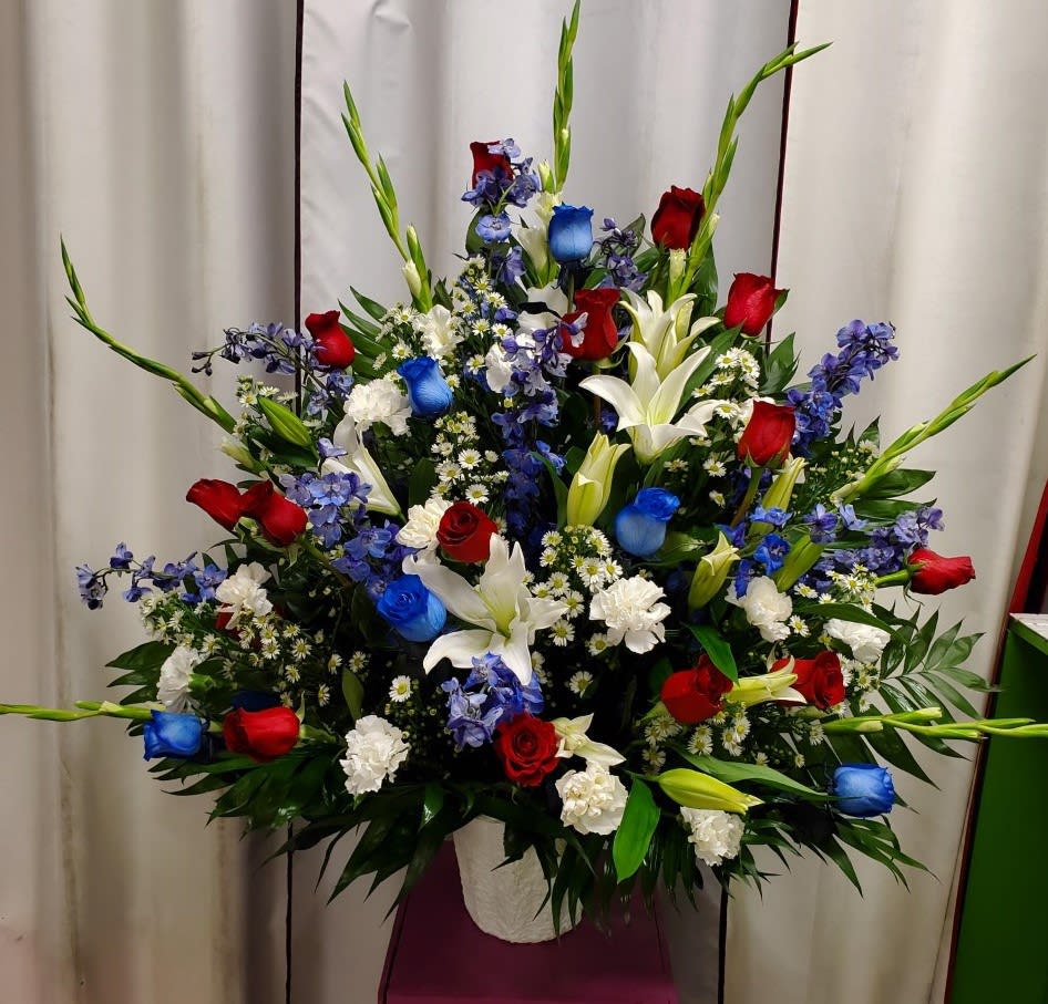 Large floral spray with red, white, and blue flowers in a white container