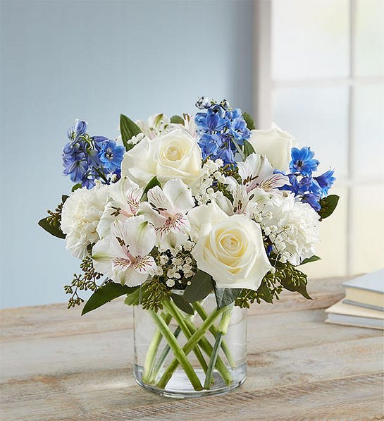 White and blue mixed bouquet in a clear glass vase
