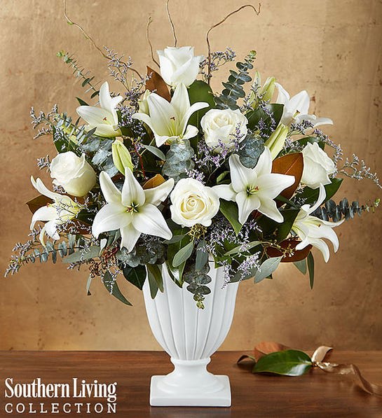 White lilies and roses arranged in a white pedestal vase