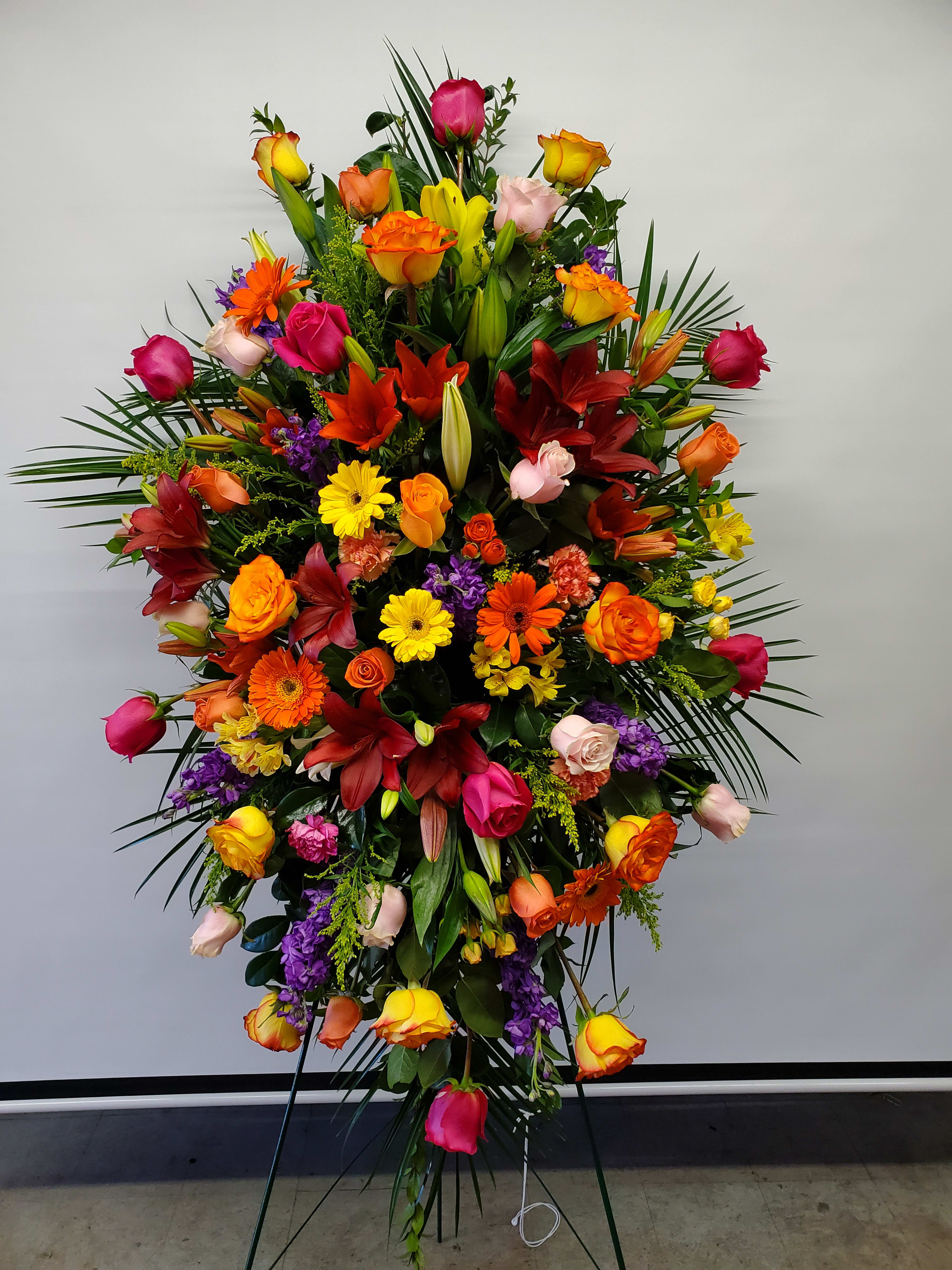 Tall standing spray of mixed roses, lilies, and gerbera daisies