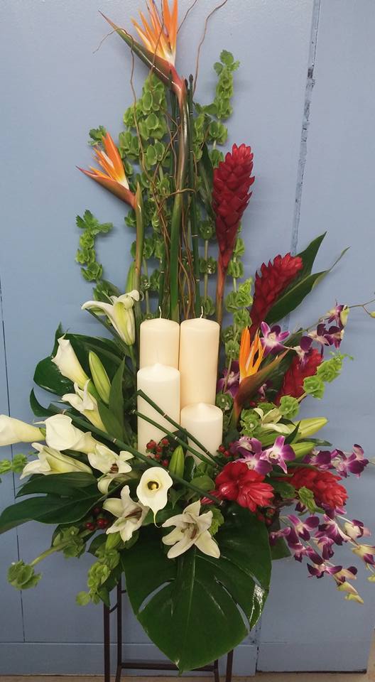 Tropical floral arrangement with white lilies, orchids, and candles