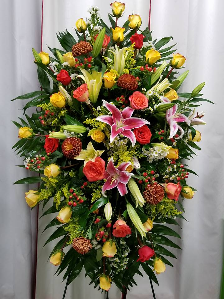 Standing floral spray with roses and lilies in yellow, pink, and red