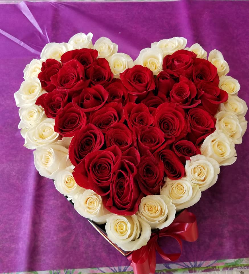 Heart-shaped bouquet of red and white roses with a red ribbon