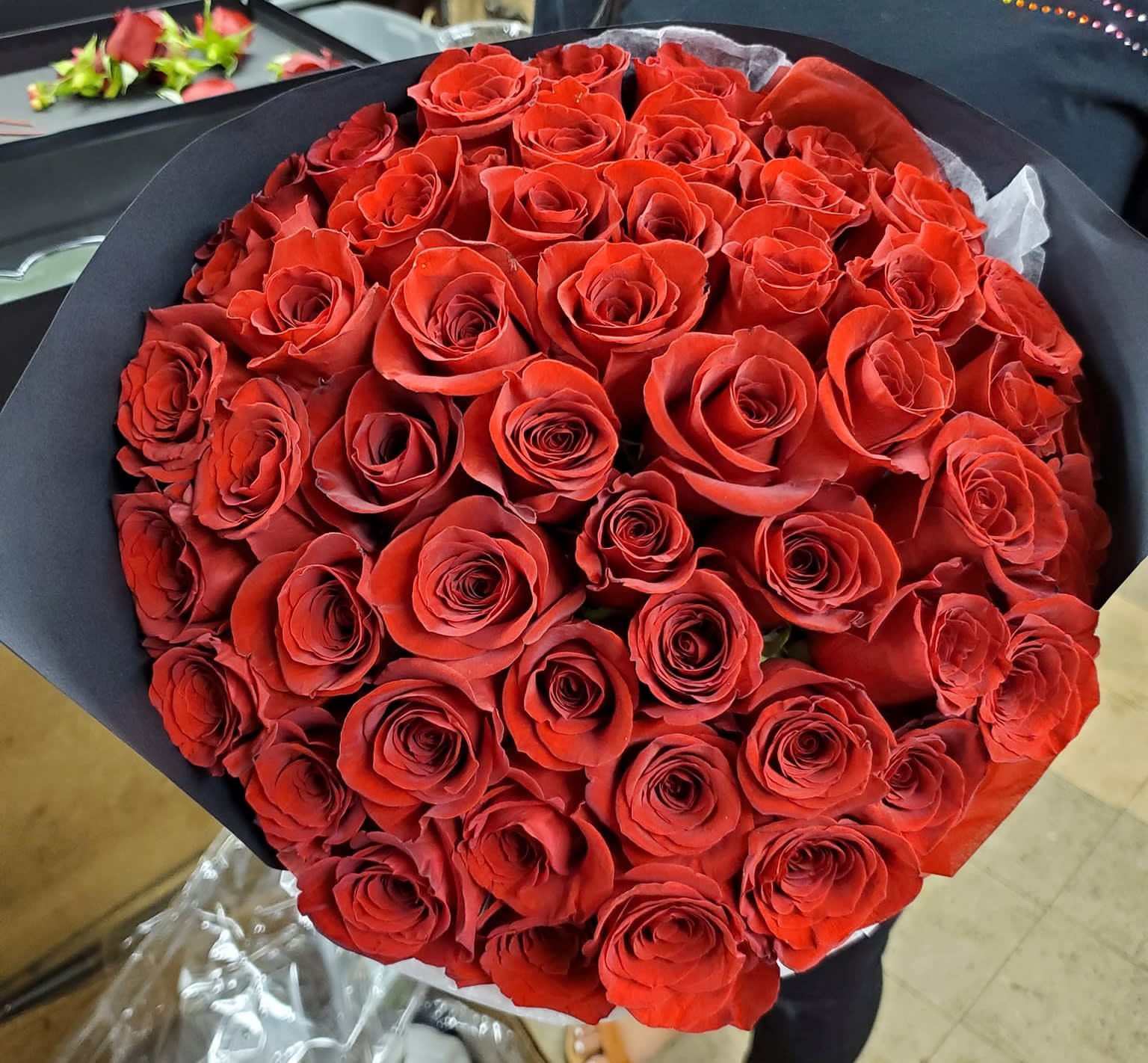 Large bouquet of red roses wrapped in black paper