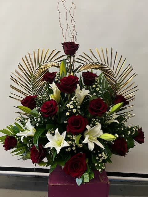 Red roses and white lilies arranged in a tall display with gold fan accents