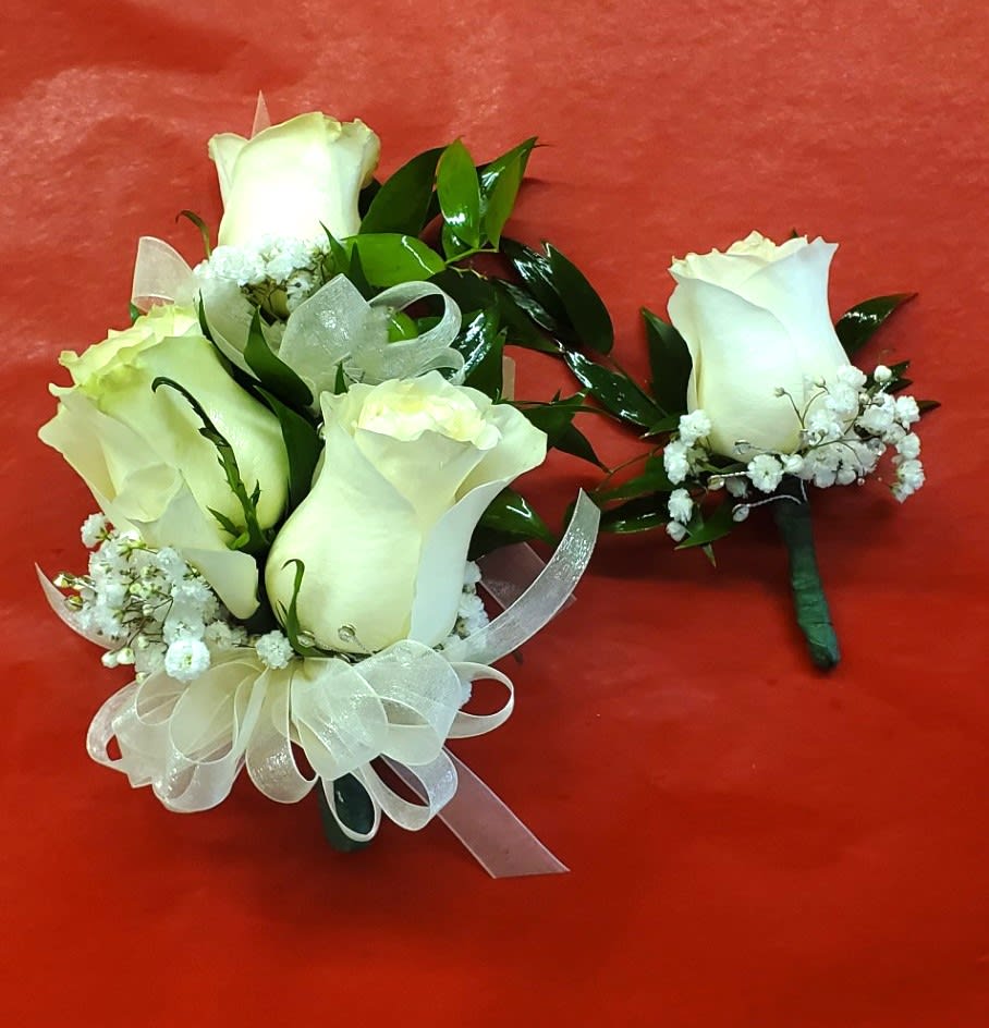 White rose bouquet and matching boutonniere with ribbon on red background