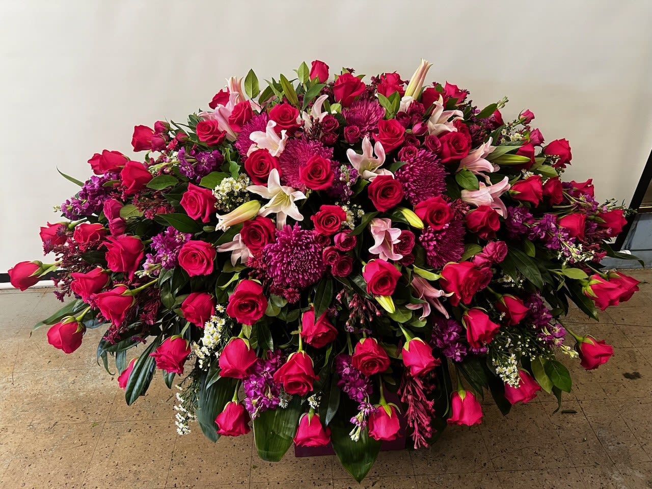 Large arrangement of pink roses, lilies, and purple flowers