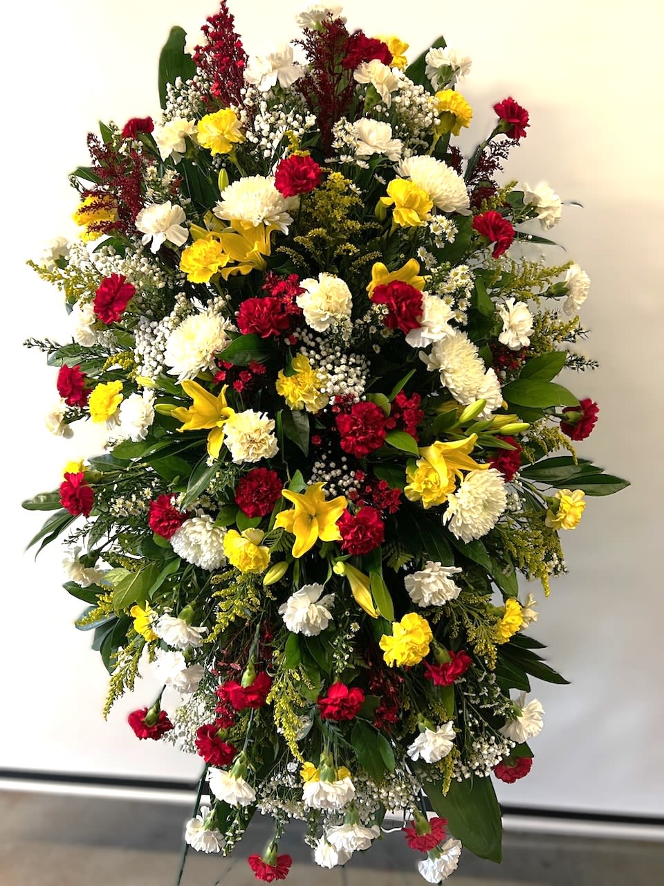 Large standing floral spray with red, white, and yellow flowers