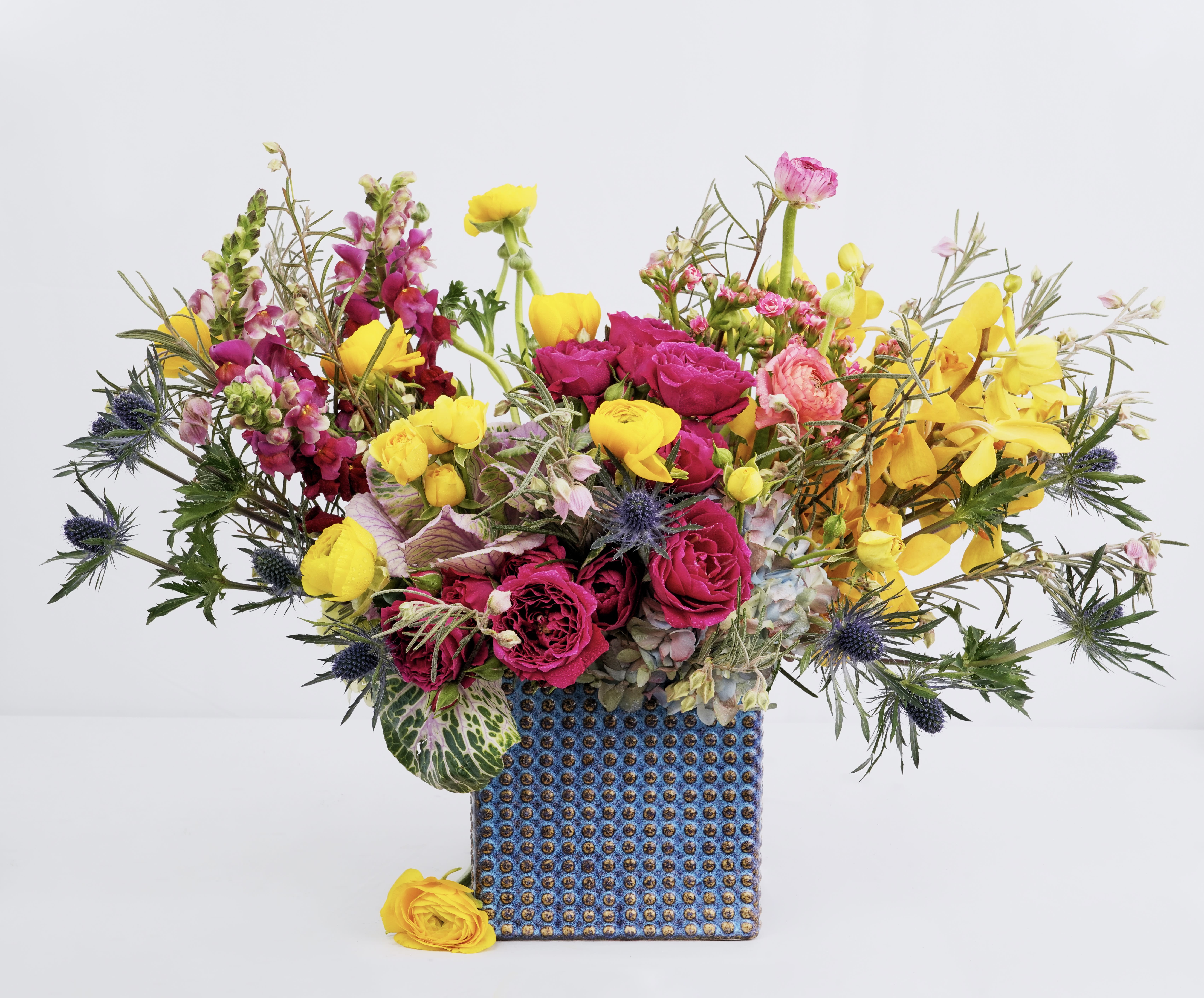Bright mixed bouquet in a blue patterned vase with yellow and pink flowers