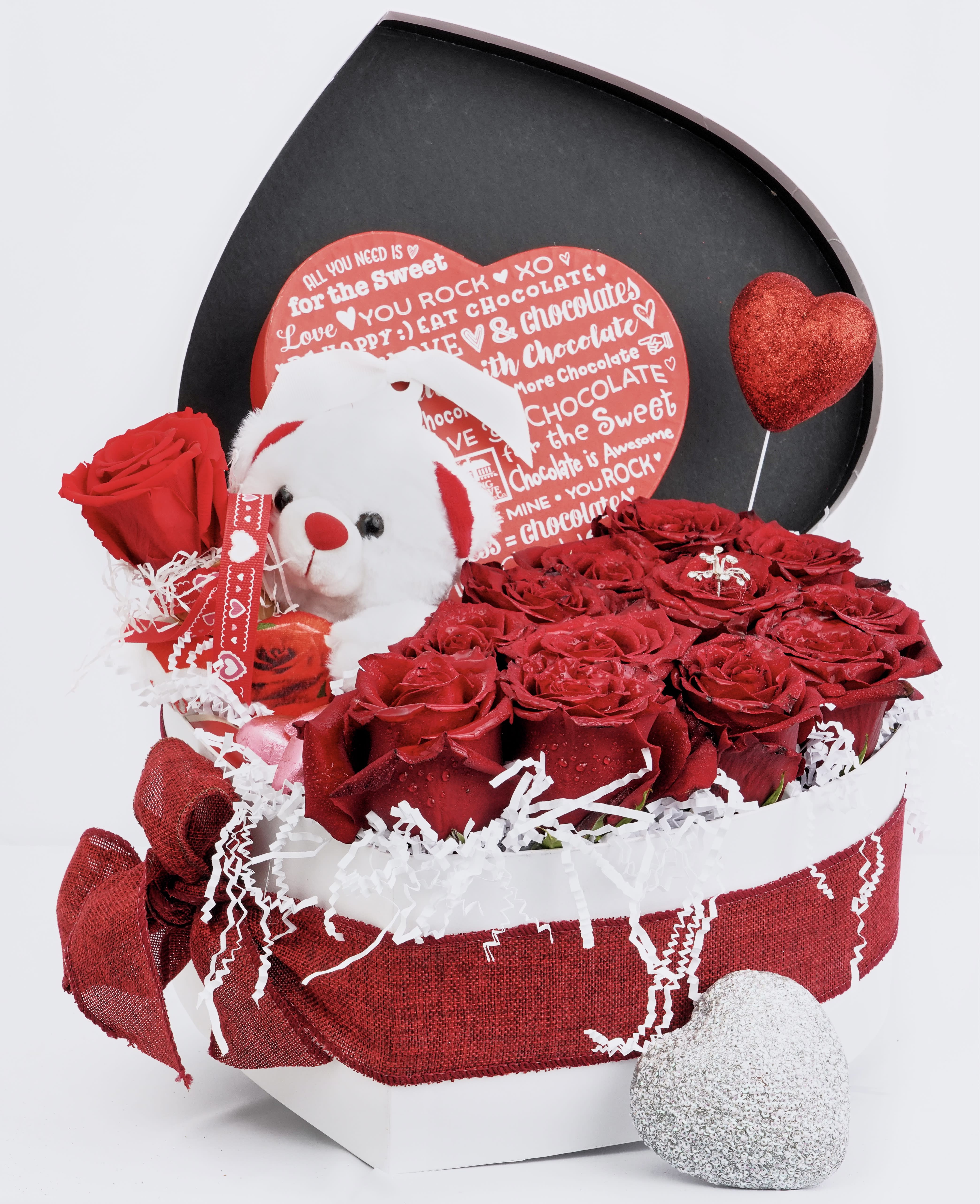 Red roses in a gift box with a teddy bear and heart decorations